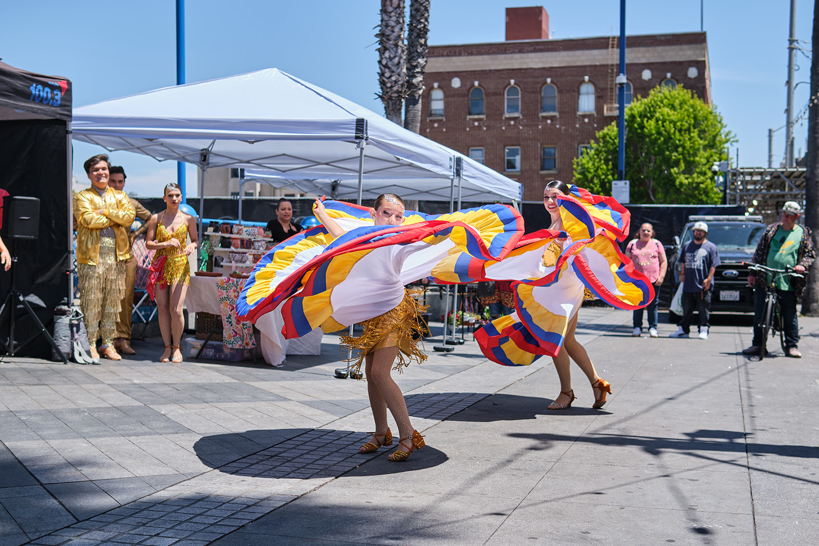 Dancers in colorful traditional skirts perform at the 16th Street BART Plaza during a Sábado Gigante activation